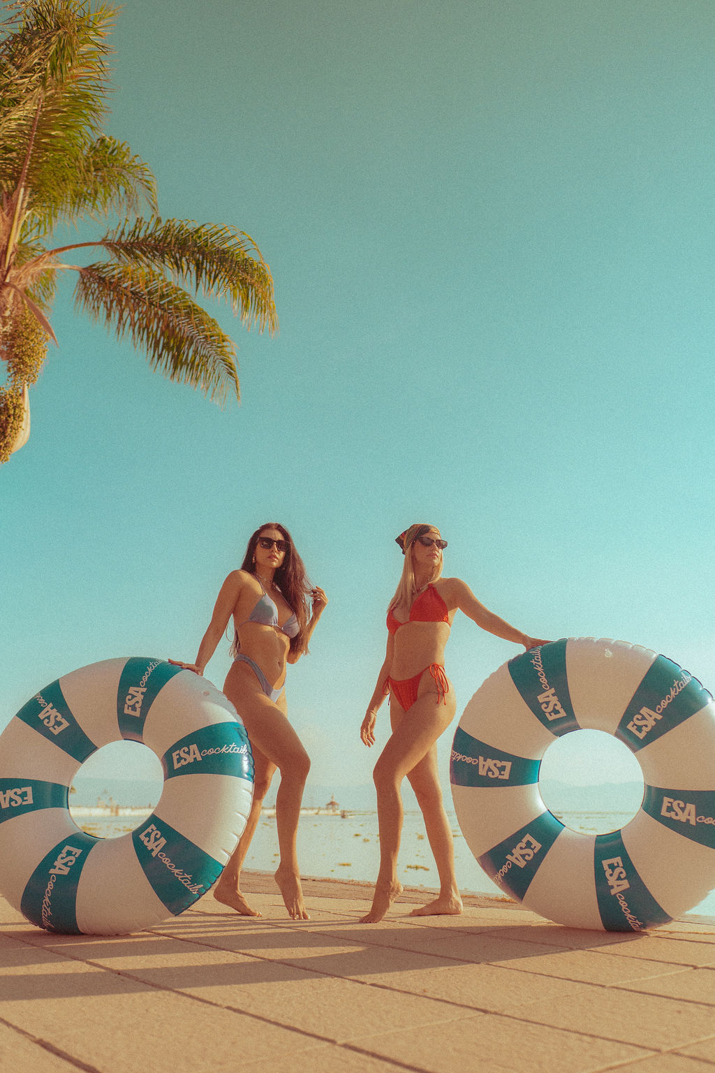 Two models with ESA branded pool floats by the water